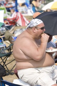 Fat shirtless guy eating a cheeseburger
